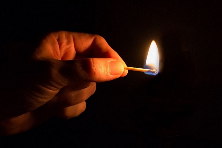 Hand mit einem brennenden Streichholz