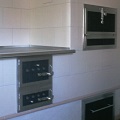 gemauerter weißer Küchenofen mit Kochplatte und schwarzen Metalltüren und Edelstahlelementen